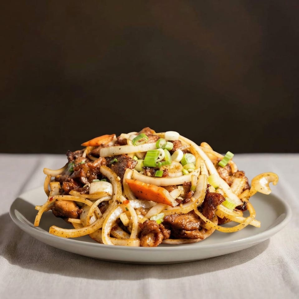 A plate of stir-fried meat and vegetables, including onions, carrots, and green onions.